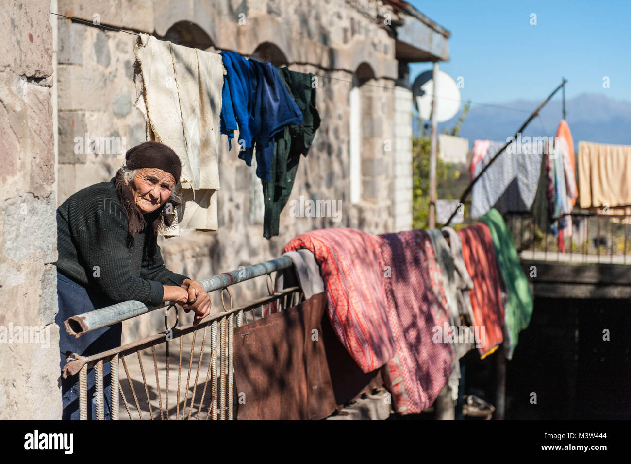 Pauvre vieille femme debout sur le balcon de sa maison à Khndzoresk communauté rurale dans le sud-est de l'Arménie. Banque D'Images