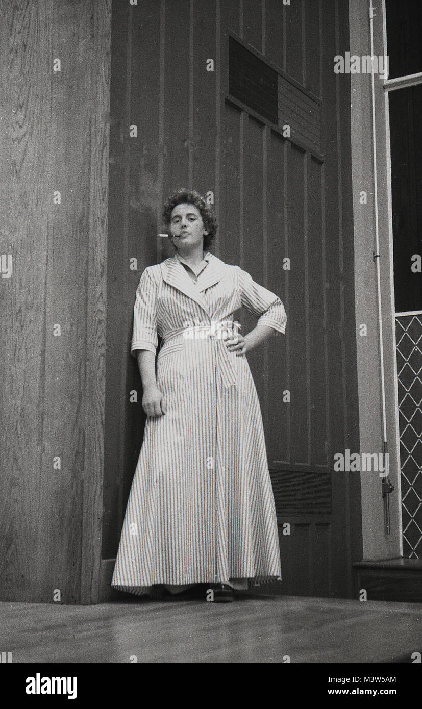 1940, historiques, une actrice Dame vêtue d'un peignoir ou robe de chambre essayant de paraître sophiscated byt fumer une cigarette à travers un porte-cigarette, sur une scène dans une pièce de théâtre, England, UK. Théâtre amateur était une activité de loisirs populaire en Grande-Bretagne d'après-guerre en ce moment. Banque D'Images