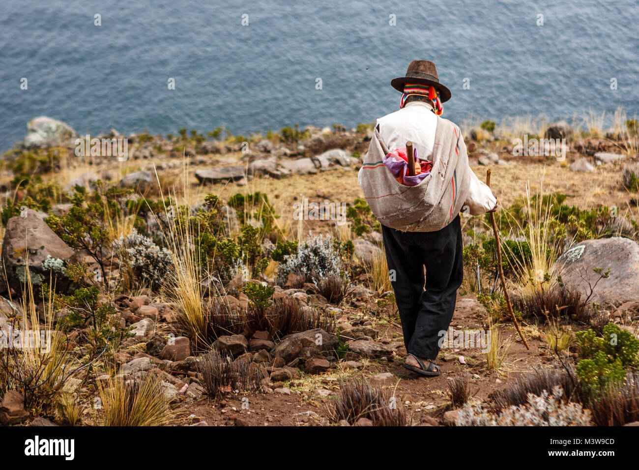 Pauvre homme vu de dos marchant sur une falaise, l'île de Taquile, lac Titicaca, Pérou Banque D'Images