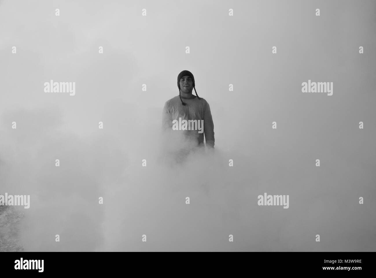 Jeune homme presque complètement cachée au milieu de la vapeur des geysers permanent au Chili Banque D'Images