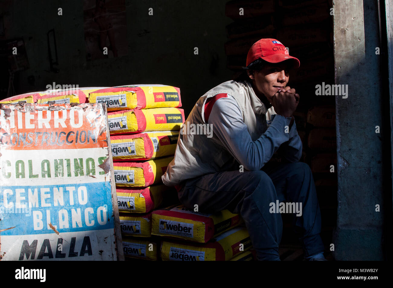 Un jeune homme posant en étant assis sur des sacs de ciment à Tarija, Bolivie Banque D'Images