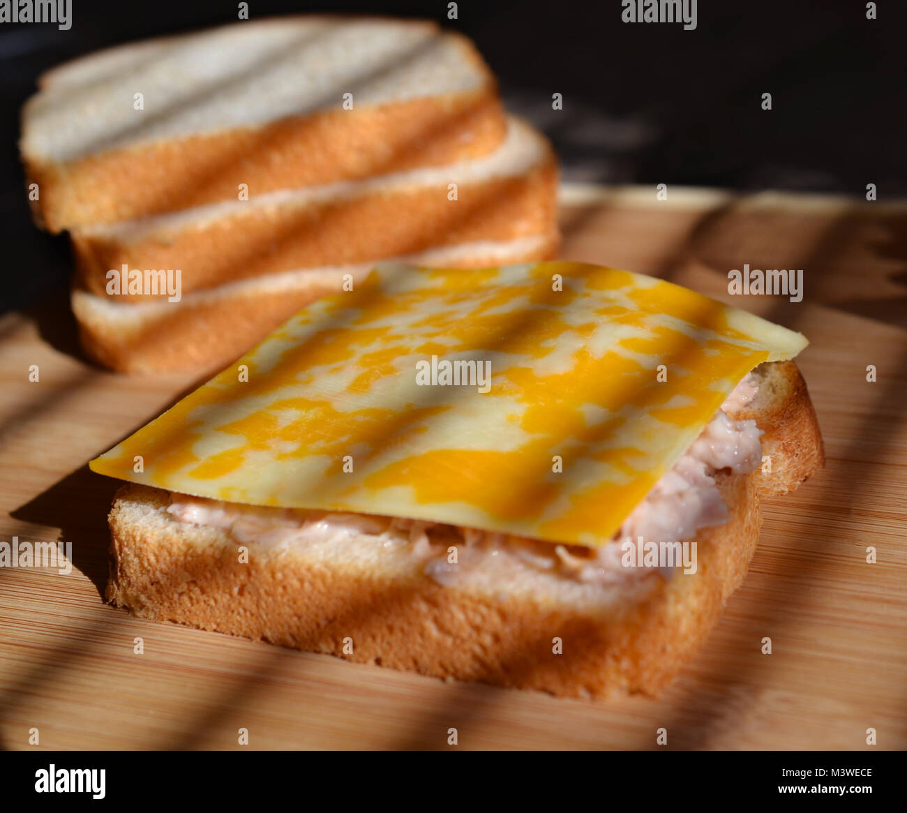 Le pain blanc avec salade de thon de propagation et mélange de fromage jaune sur blanc légèrement teinté. Le pain blanc en arrière-plan. Banque D'Images