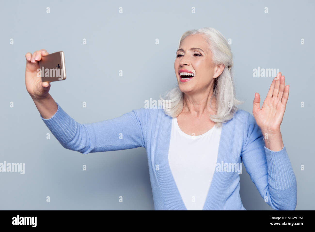 Portrait de heureux gai joyeux joyeux charmante charmante dame mature granny tourist en utilisant son smatphone pour appel vidéo, elle est en agitant avec une main Banque D'Images