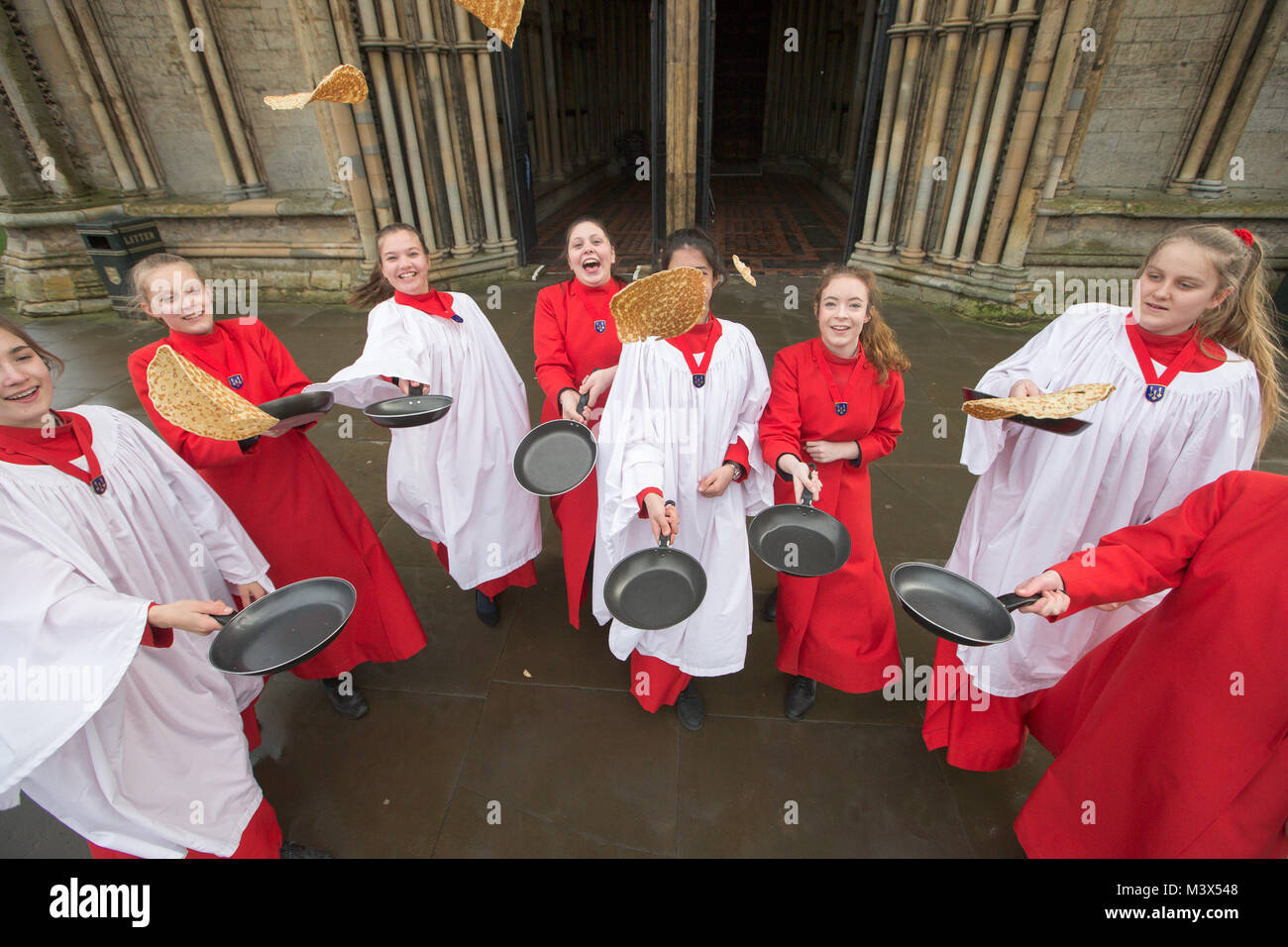 Les Choristes à partir de la cathédrale d'Ely dans le Cambridgeshire pratiquer pour ce qui est de la course de crêpes années lieu le Mardi Gras ( Feb 13) dans la cathédrale. Les Choristes ont été occupés à pratiquer pour la traditionnelle course de crêpes à la Cathédrale d'Ely dans le Cambridgeshire demain (mardi). Les filles, vêtus de leurs soutanes rouges, perfectionné leurs compétences pour lancer de crêpes l'événement annuel dans la Cathédrale du xiie siècle. Chaque année autour de 20 choristes de la Boys' and Girls' choirs dévalez la nef après la messe à l'occasion de Mardi Gras. Il est le troisième plus long nef au Royaume-Uni, mesure 75 mètres. Banque D'Images