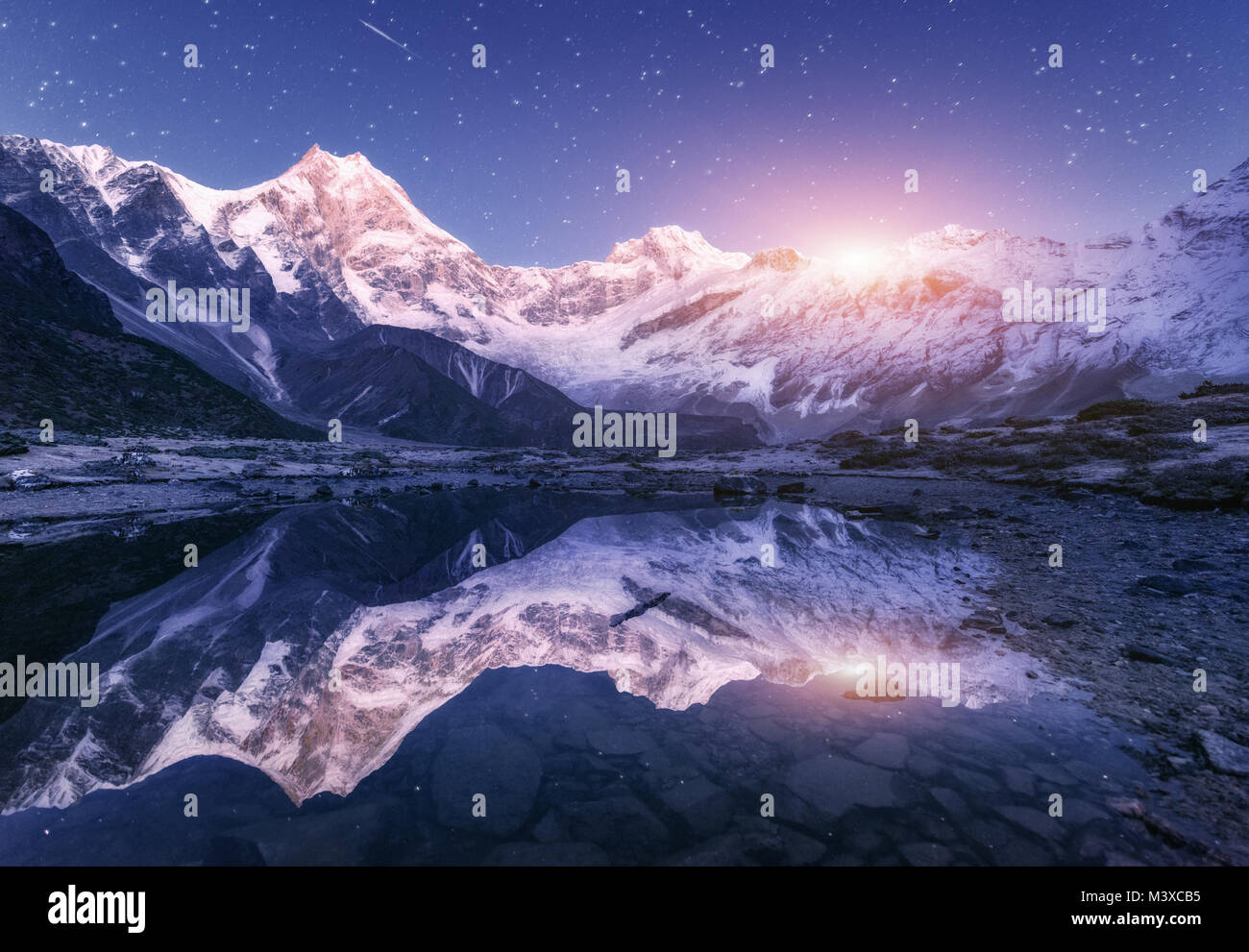 Scène de nuit avec des montagnes de l'himalaya et lac de montagne à la nuit étoilée au Népal. Paysage avec de hautes roches avec pic enneigé et le ciel avec des étoiles et de la lune Banque D'Images