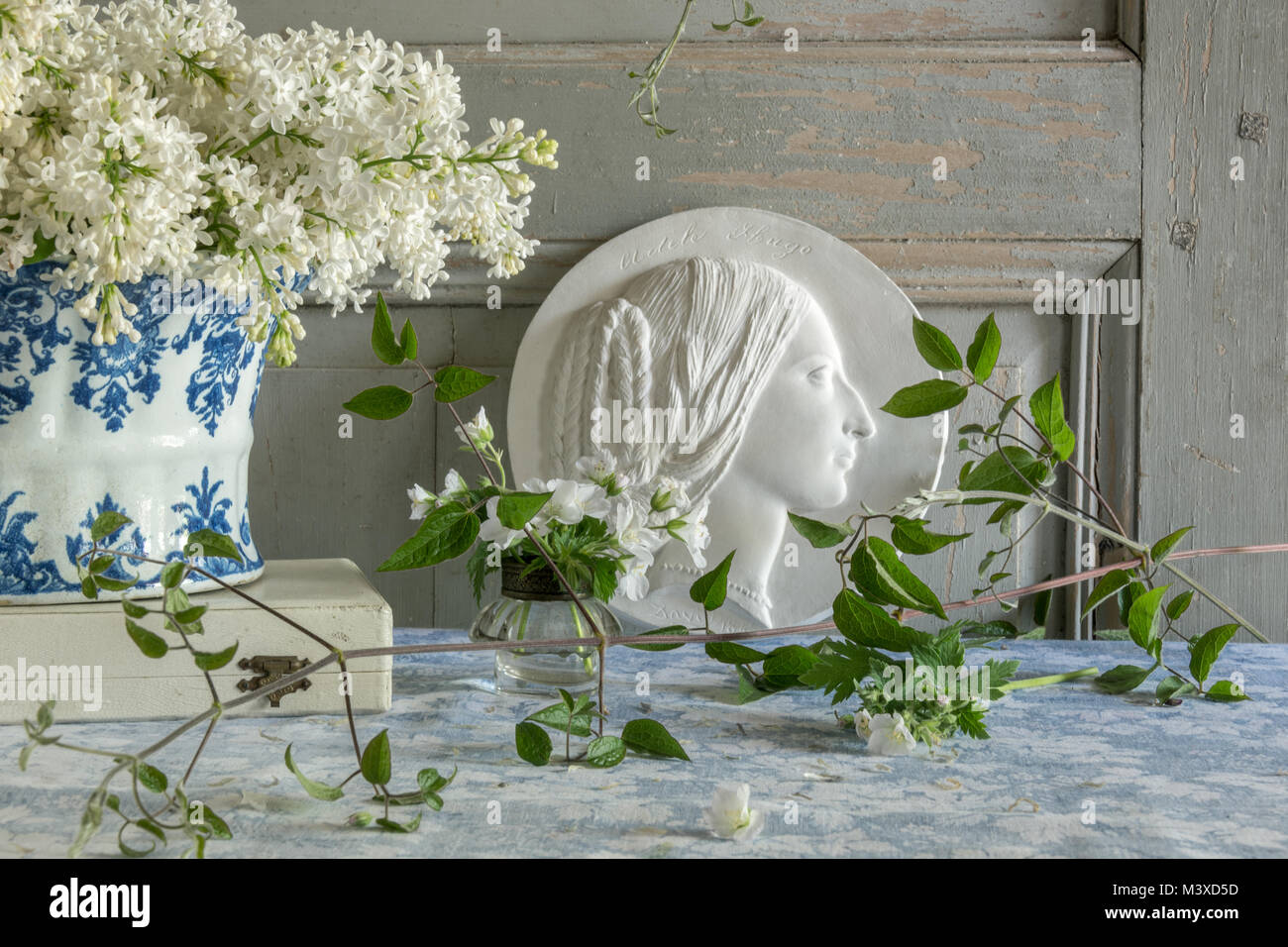 La vie encore français avec des lilas, bleu et blanc fleur antique titulaire et un médaillon en plâtre portrait Banque D'Images