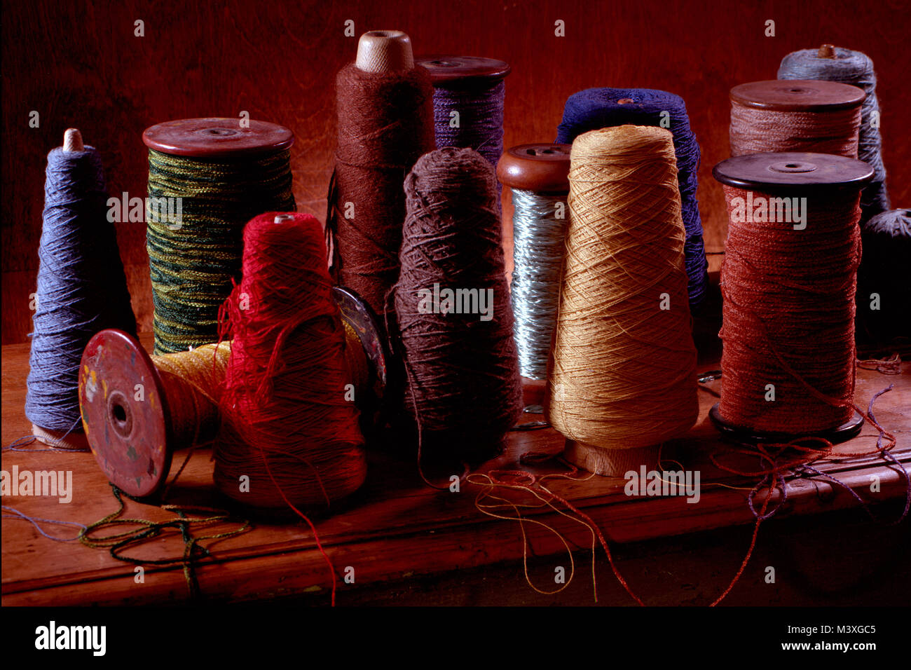 Plusieurs bobines de tissage du coton ou de la laine avec filetage sur eux. Photographie couleur vertical tourné dans un studio avec un éclairage spectaculaire. Ocre foncé Banque D'Images