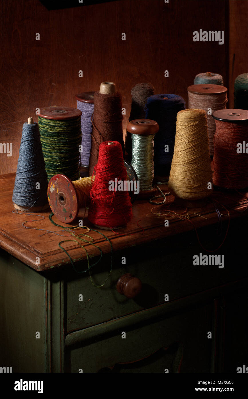 Plusieurs bobines de tissage du coton ou de la laine avec filetage sur eux. Photographie couleur vertical tourné dans un studio avec un éclairage spectaculaire. Ocre foncé Banque D'Images