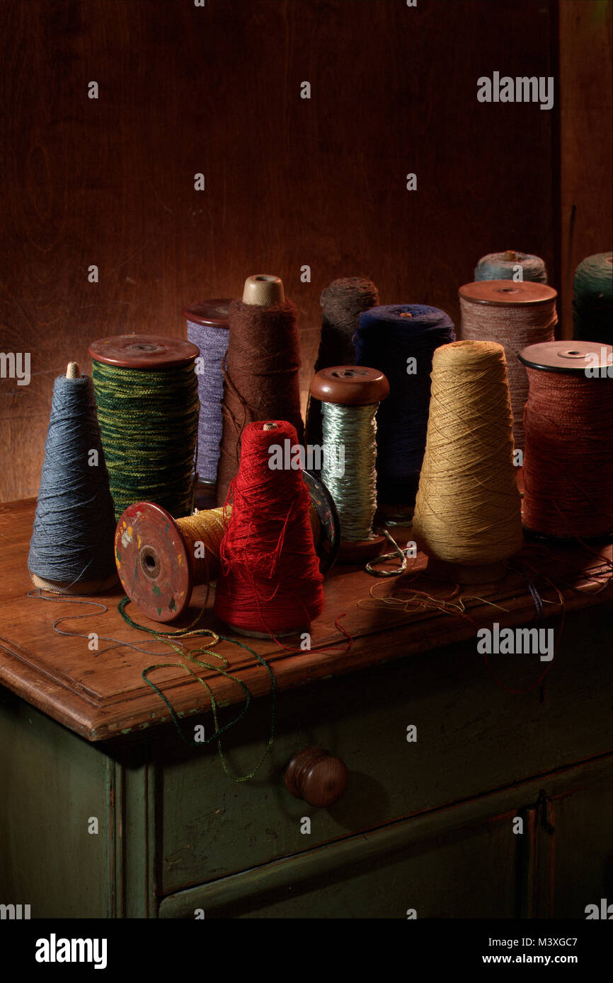 Plusieurs bobines de tissage du coton ou de la laine avec filetage sur eux. Photographie couleur vertical tourné dans un studio avec un éclairage spectaculaire. Ocre foncé Banque D'Images