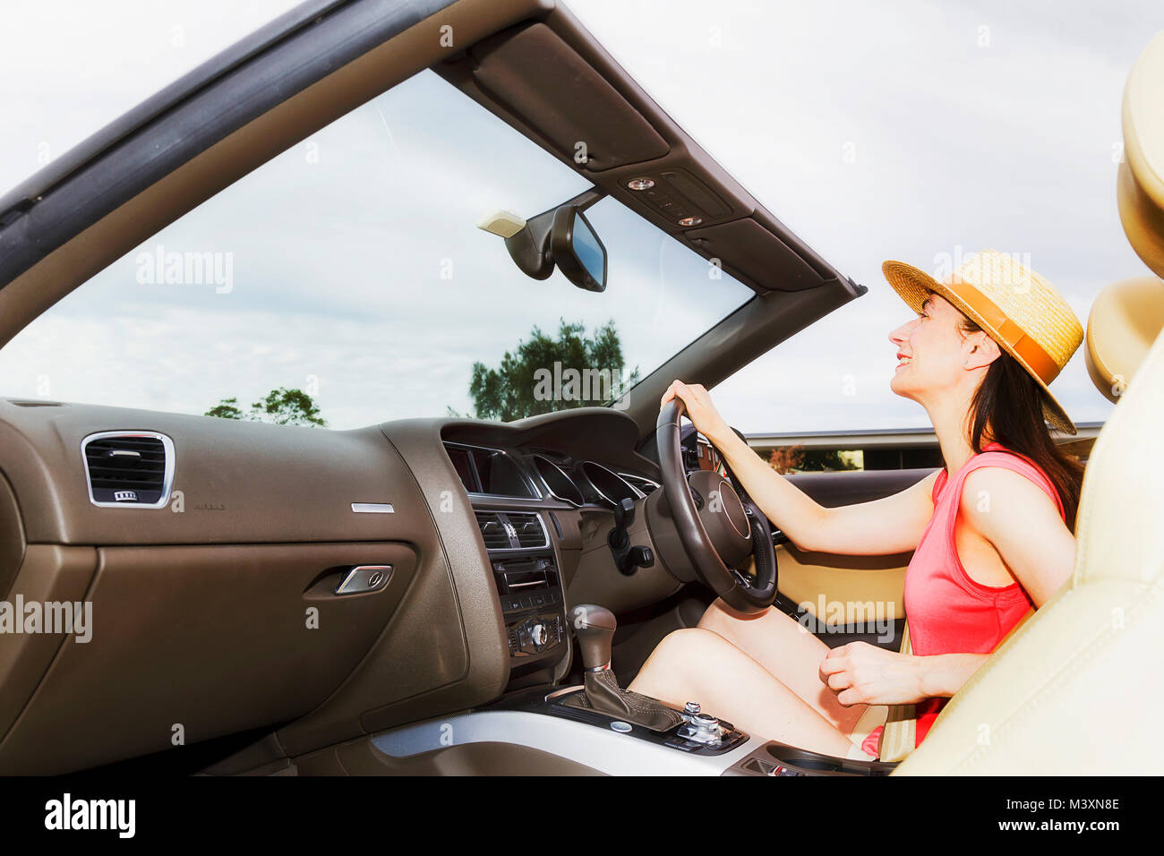 Jeune femme assise conducteur du luxe moderne voiture décapotable avec capote ouverte en vertu de l'open sky Conduite et direction de la liberté. Banque D'Images