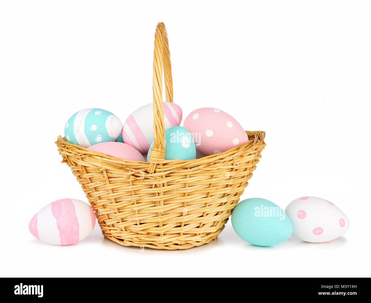 Panier rempli de Pâques peints à la main de couleur rose, bleu et blanc d'oeufs de Pâques sur un fond blanc Banque D'Images