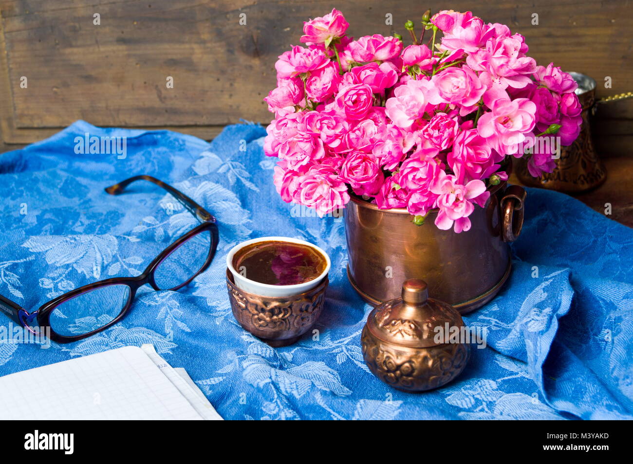 Roses rose et une tasse de café dans une tasse en cuivre Banque D'Images