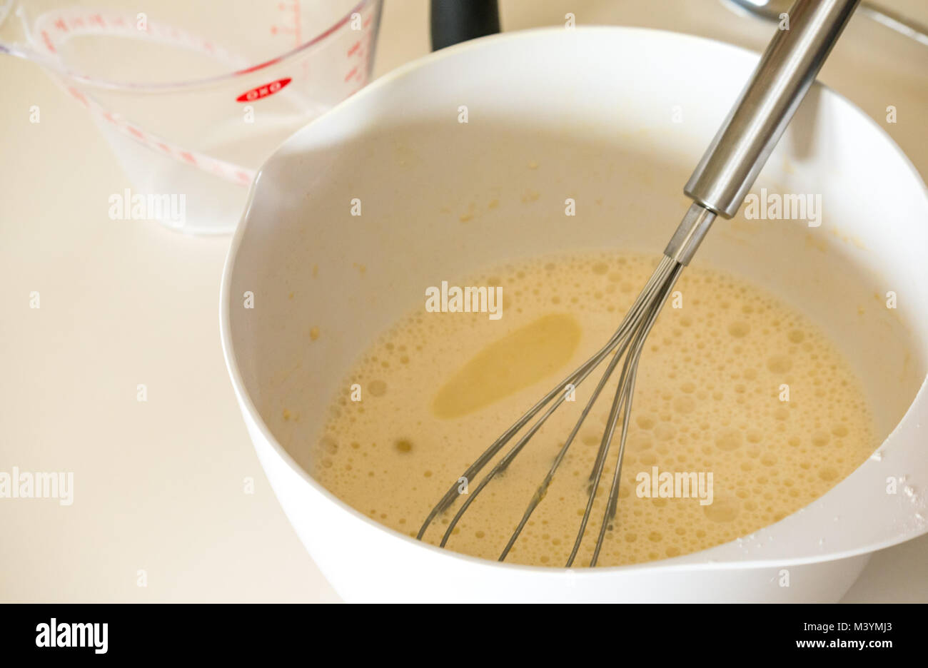 La pâte à crêpes prêt à fouetter pendant le Mardi gras avec la farine, le lait, les œufs et l'huile dans une cuisine maison Banque D'Images