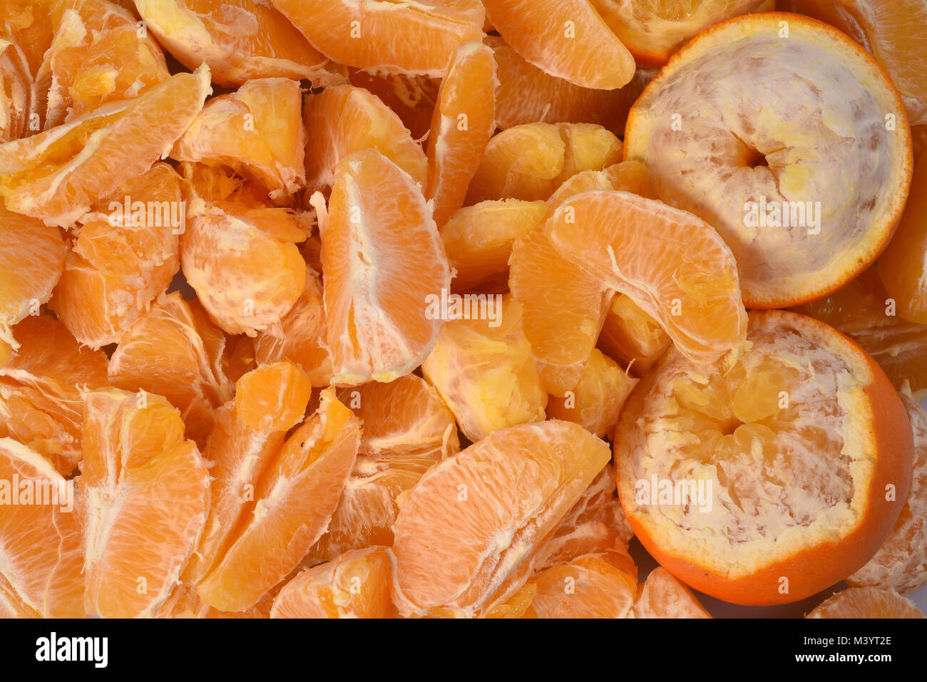 De nouvelles matières premières pour le jus d'orange frais : un grand nombre de tranches d'orange et sur la droite deux demi-fruits épluchés. Banque D'Images