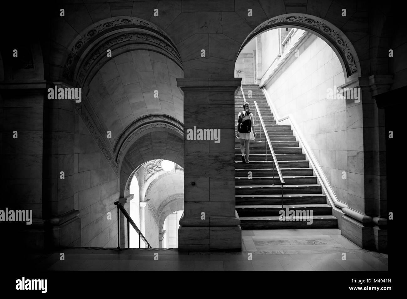 New York Public Library de l'intérieur. Image en noir et blanc d'une fille qui marche à travers une arcade et un peu d'escaliers. Banque D'Images