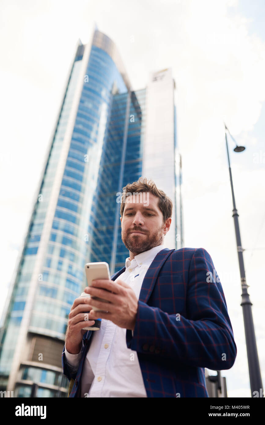 Young businessman standing dans la ville la lecture de messages texte Banque D'Images