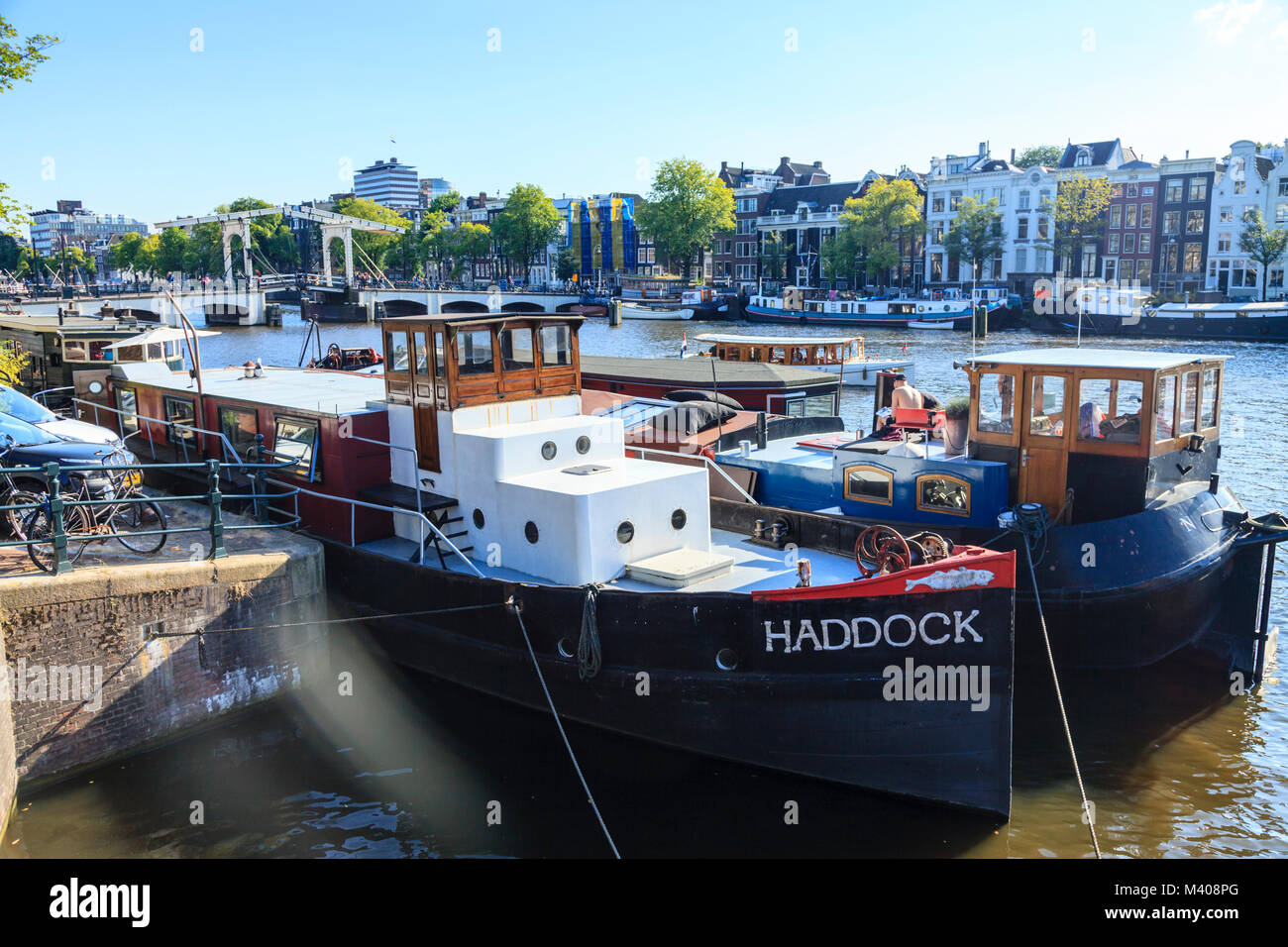 Les chalands amarrés sur l'Amstel, dans le centre d'Amsterdam. Le Magere Brug, le pont Maigre, est dans l'arrière-plan. Banque D'Images