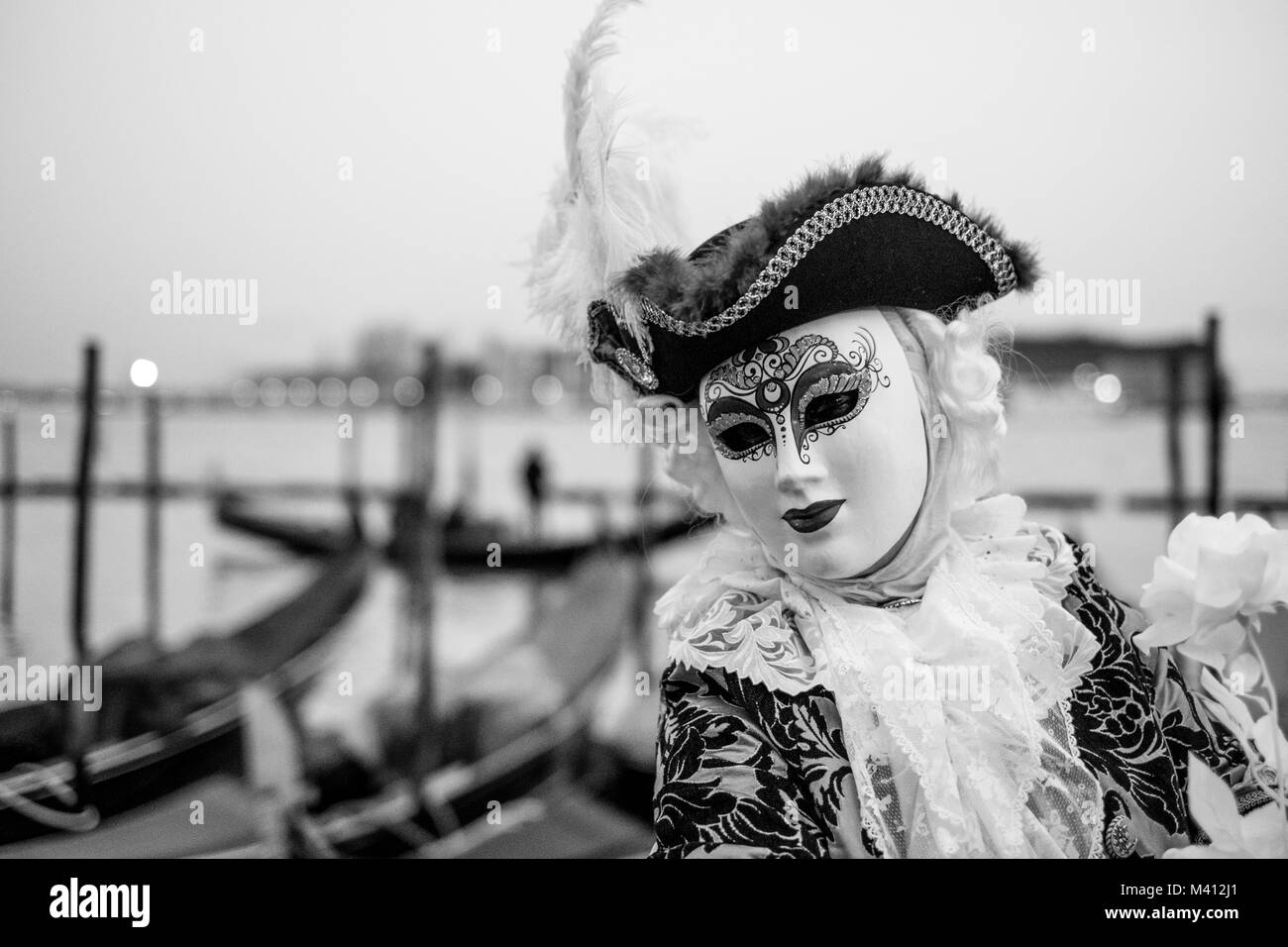 Carnaval de sexe masculin pratiquant en costume traditionnel et masque debout avec retour à le Grand Canal, les gondoles et San Giorgio en arrière-plan Banque D'Images