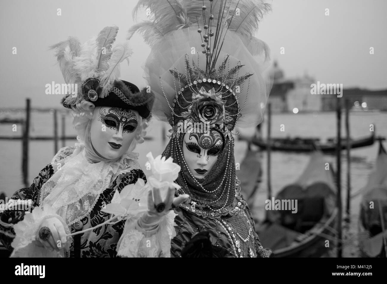 Couple en costume traditionnel et des masques avec permanent retour à le Grand Canal, les gondoles et San Giorgio en arrière-plan, au cours de la carnaval de Venise. Banque D'Images