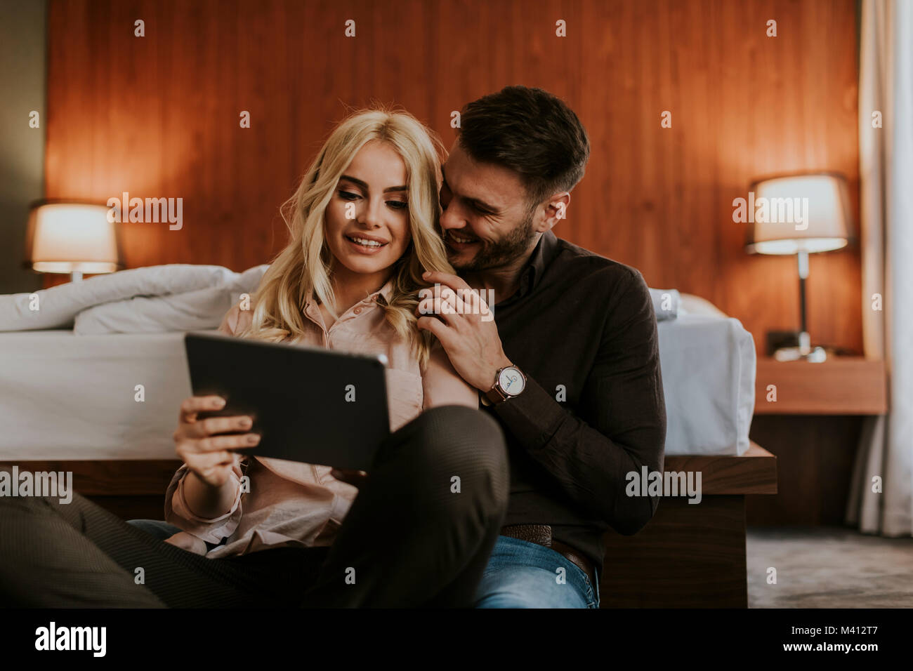 Couple d'amoureux assis sur le plancher dans la chambre et using digital tablet Banque D'Images