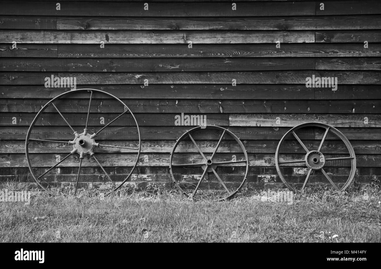 De l'image monochrome rouille 3 roues de chariot appuyé contre une grange en bois. Banque D'Images
