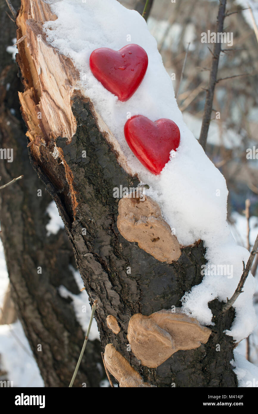 Deux figurines en bois peint en rouge en forme de coeur sur la neige Banque D'Images