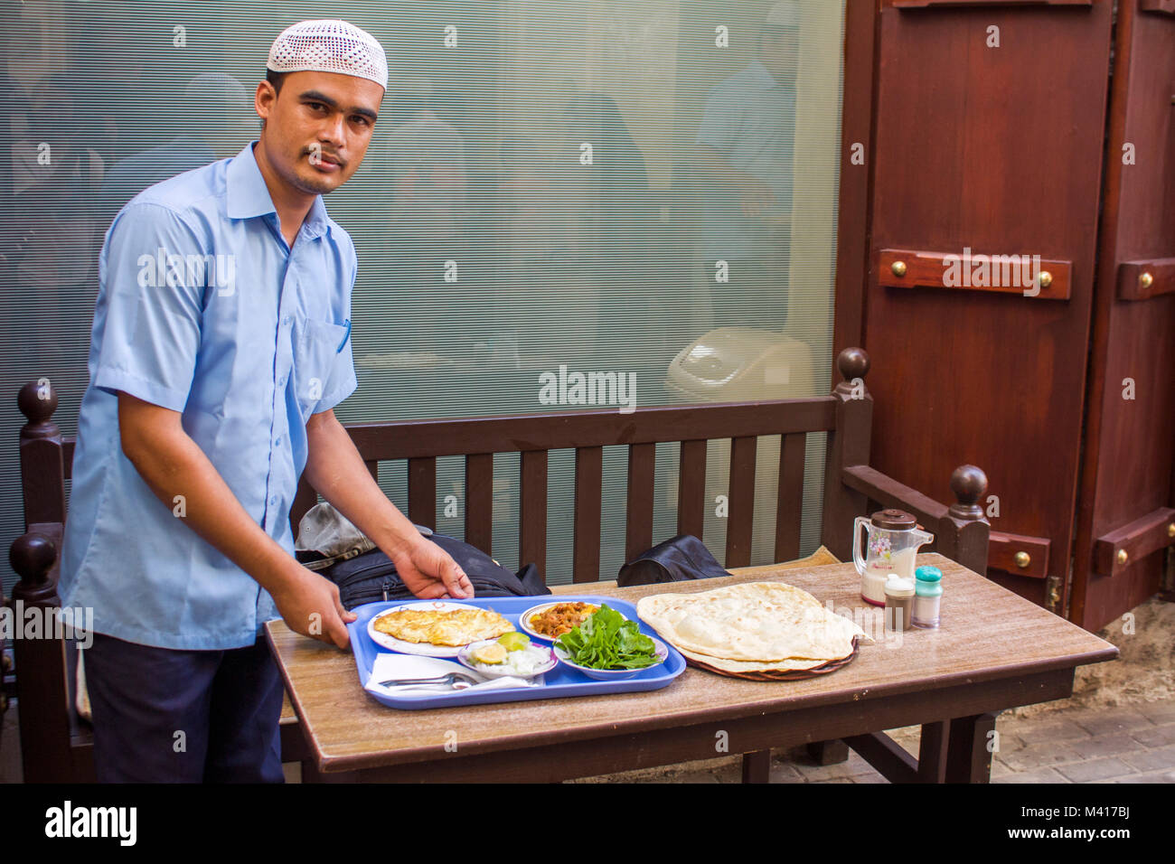 Serveur qui sert le petit-déjeuner pour le client à un bazar à Mnama, Bahreïn.La plupart des travailleurs dans la région du Moyen-Orient viennent de d'Asie du sud, Banque D'Images