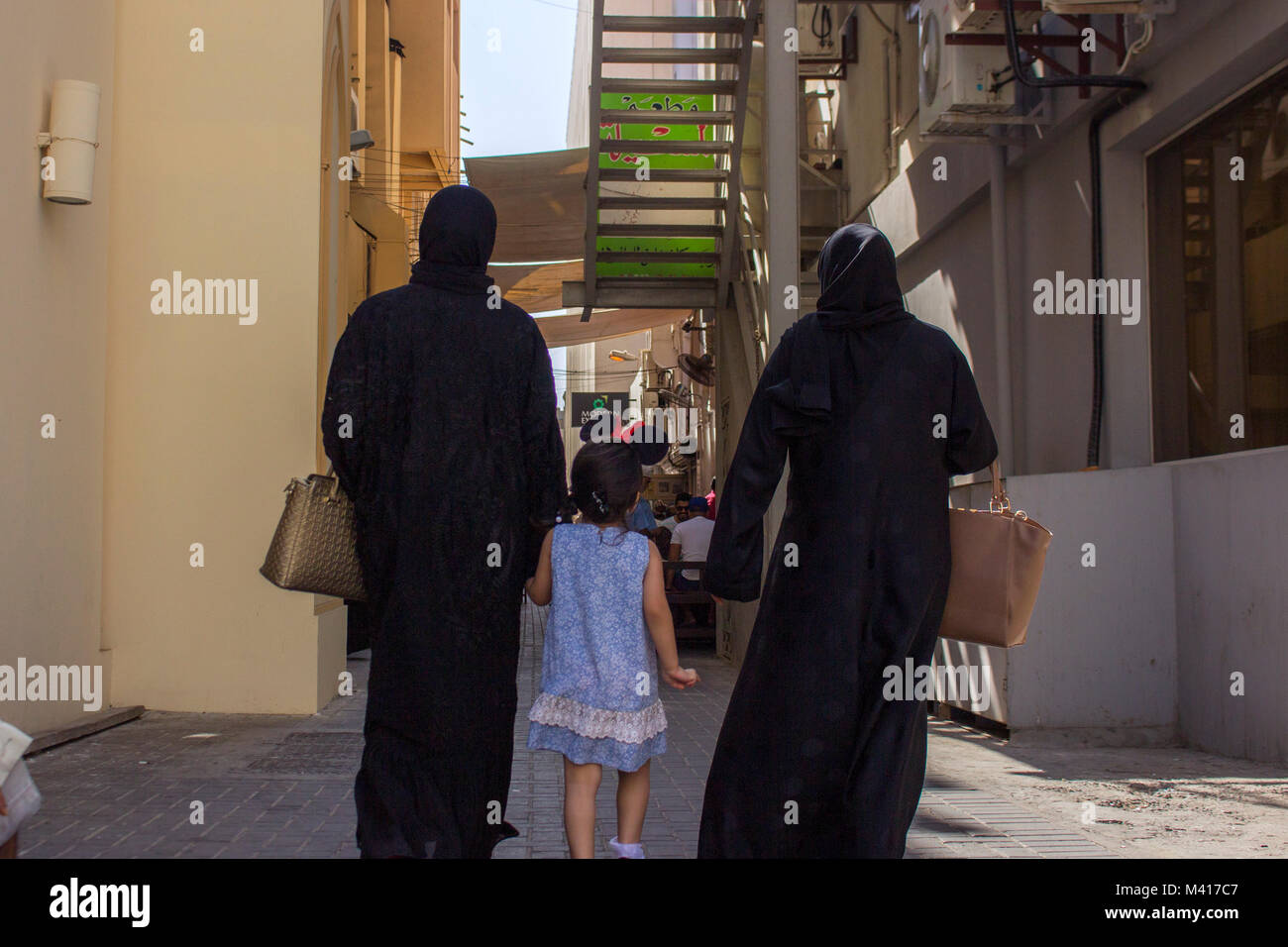 Moyen orient femme amener son enfant à l'extérieur, marcher dans une allée portant burqa Banque D'Images