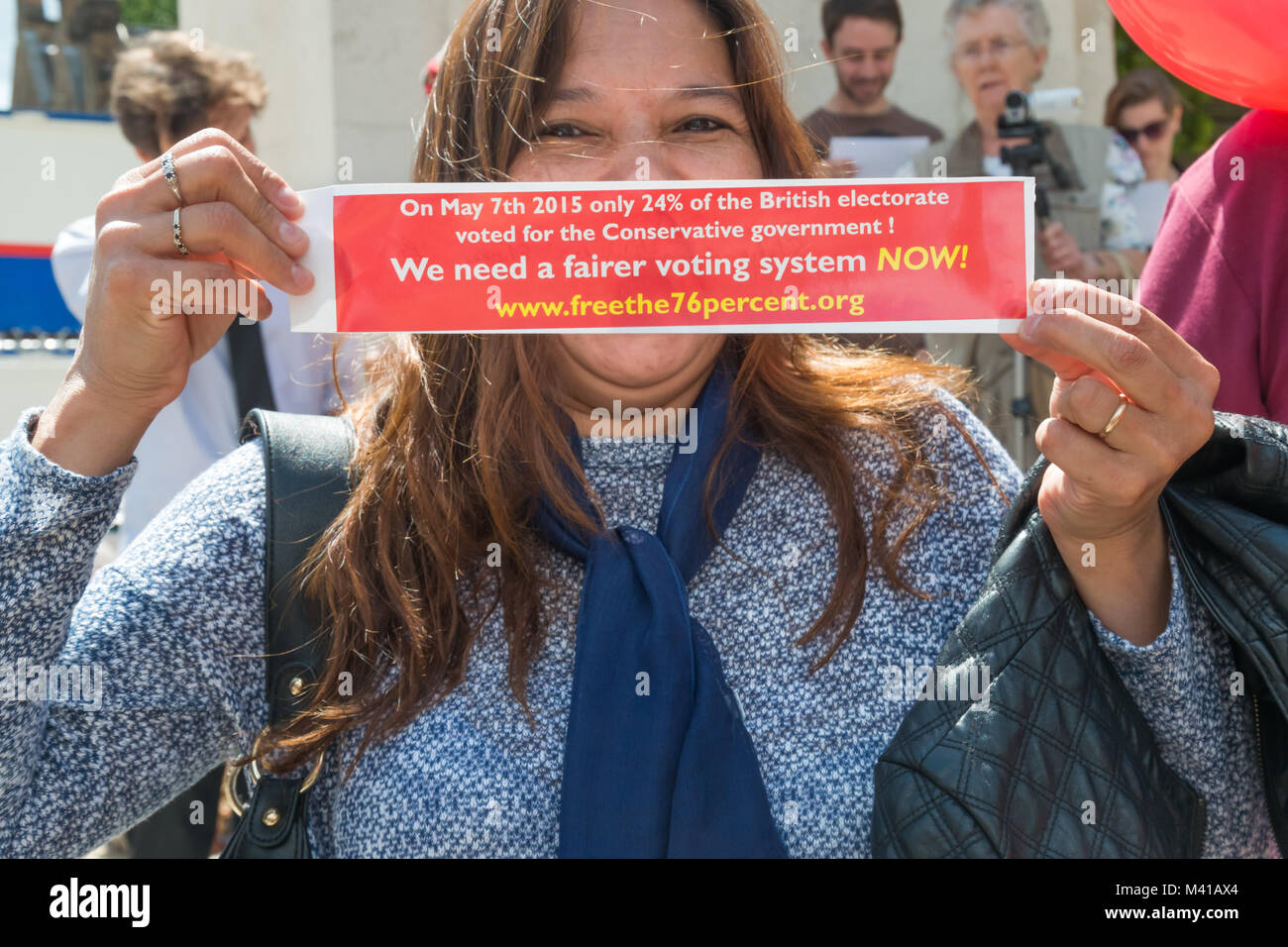 Une femme nous tend un message 'un 7 mai 2015 que 24 % de l'électorat britannique ont voté pour le gouvernement conservateur ! Nous avons besoin d'un système de vote plus équitable MAINTENANT !' en face du hwer bouche. Banque D'Images