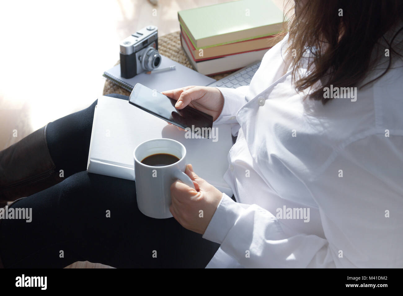 Femme assise sur un sol en bois blanc en utilisant un mobile connecté à Internet. L'employé de faire travailleur quelques formalités administratives. Copie vide de l'espace pour l'éditeur Banque D'Images