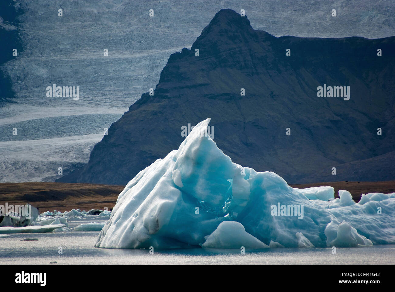 Iceber flotte sur l'eau froide du lac glaciaire Jokursarlon et,sur arrière-plan, le glacier de Vatnajokull, Islande Banque D'Images