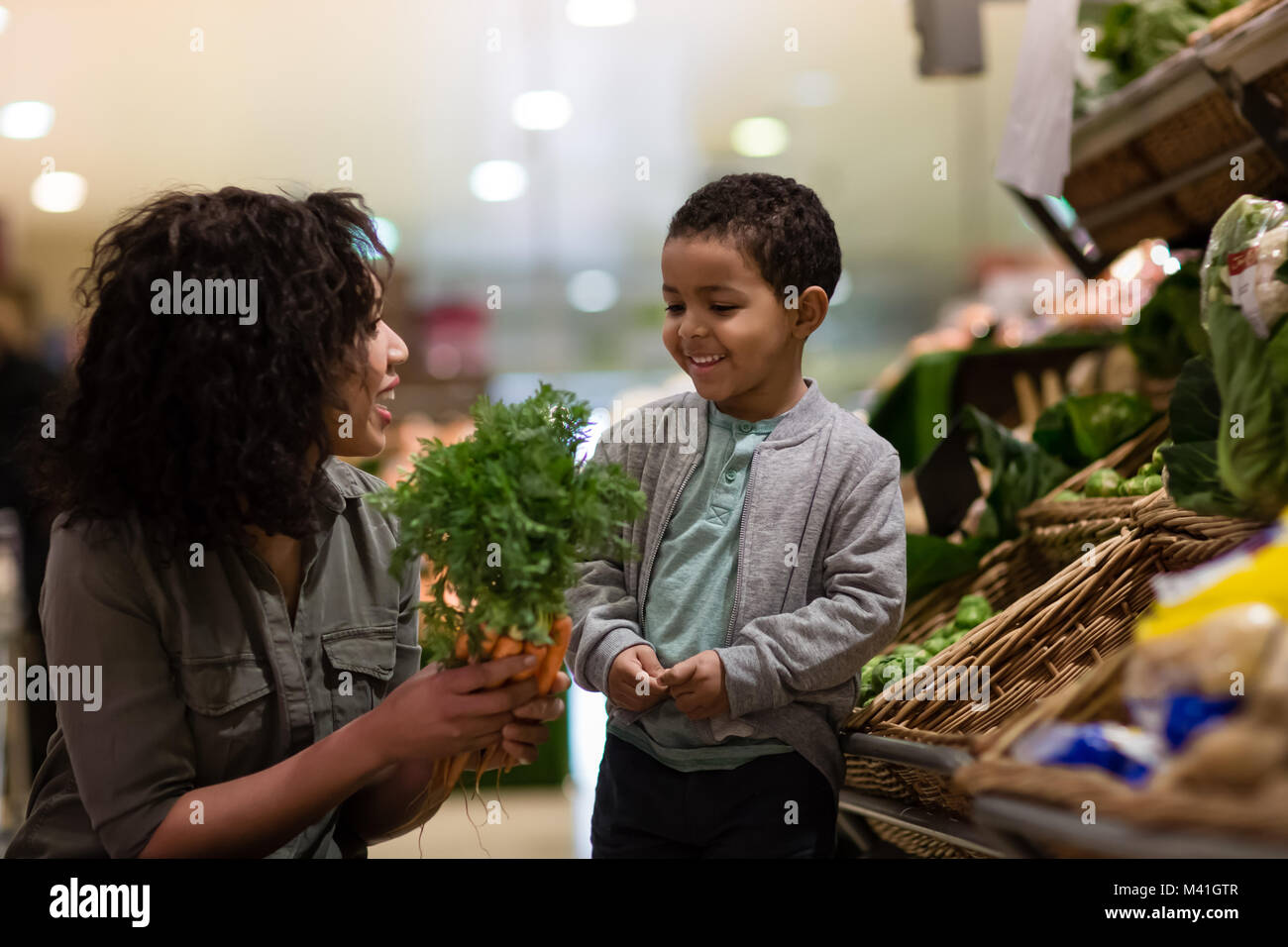 Boy picking carrots in grocery store Banque D'Images