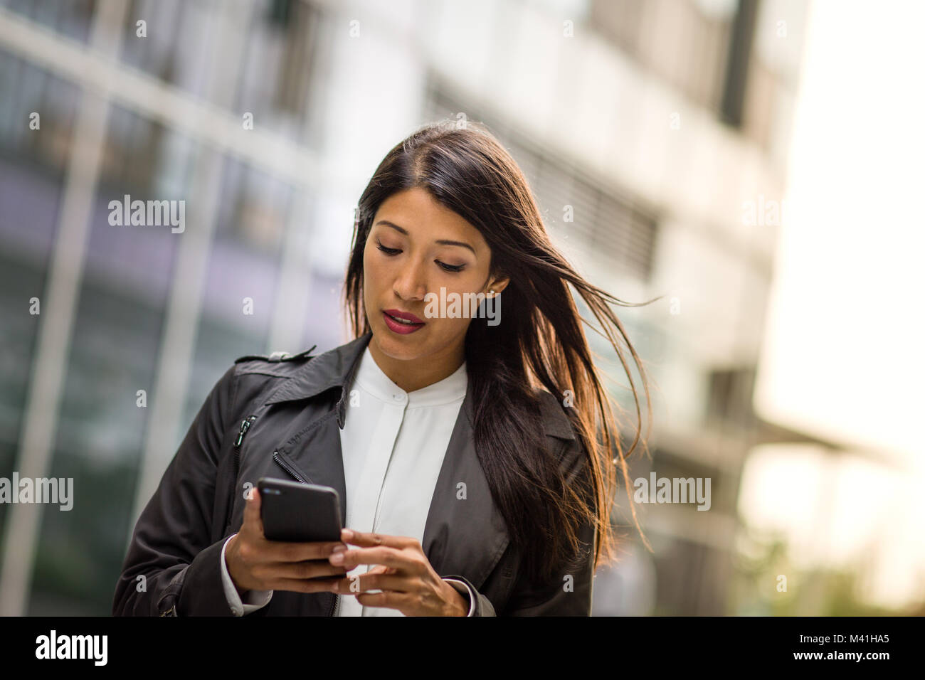 Businesswoman outdoors using smartphone Banque D'Images