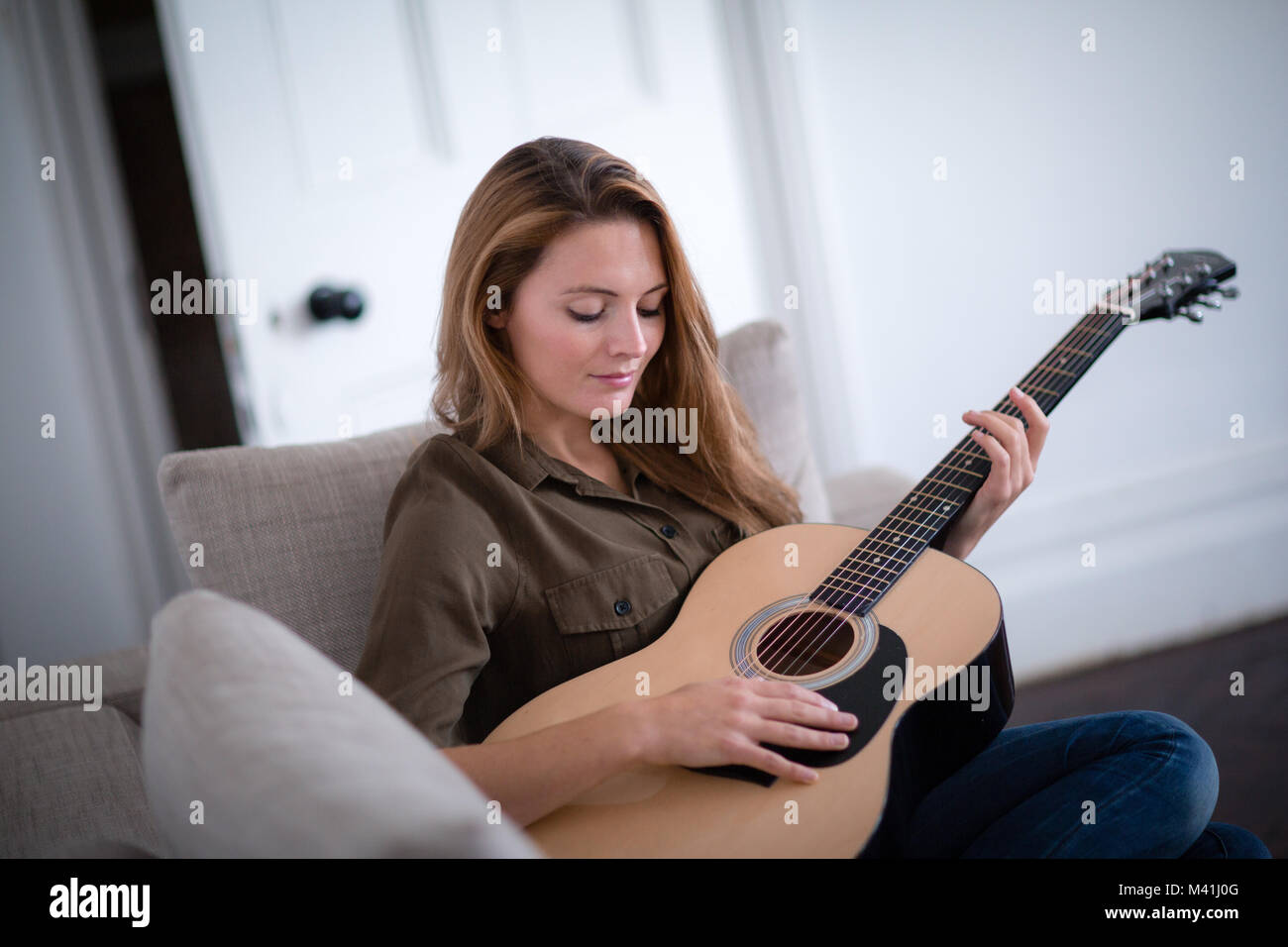 Les jeunes femelles adultes playing acoustic guitar Banque D'Images