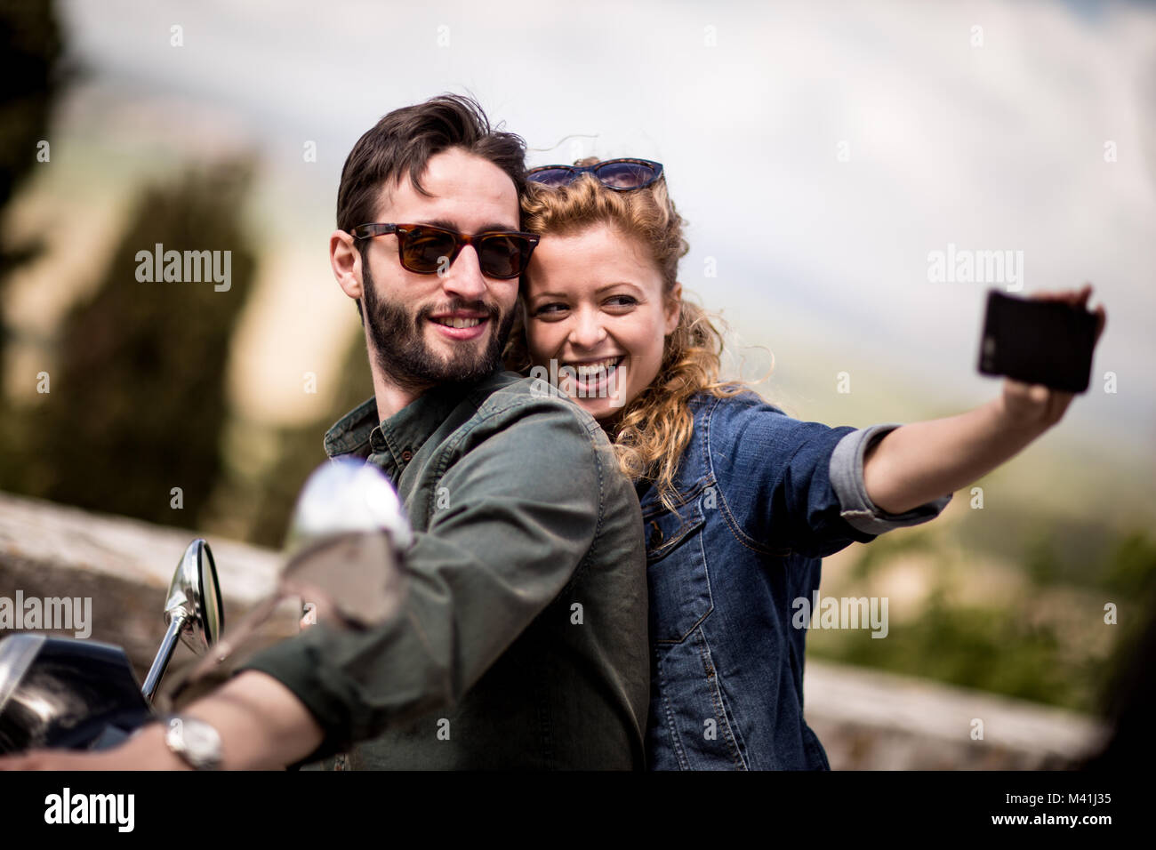 Jeune couple en moto en tenant un selfies Banque D'Images