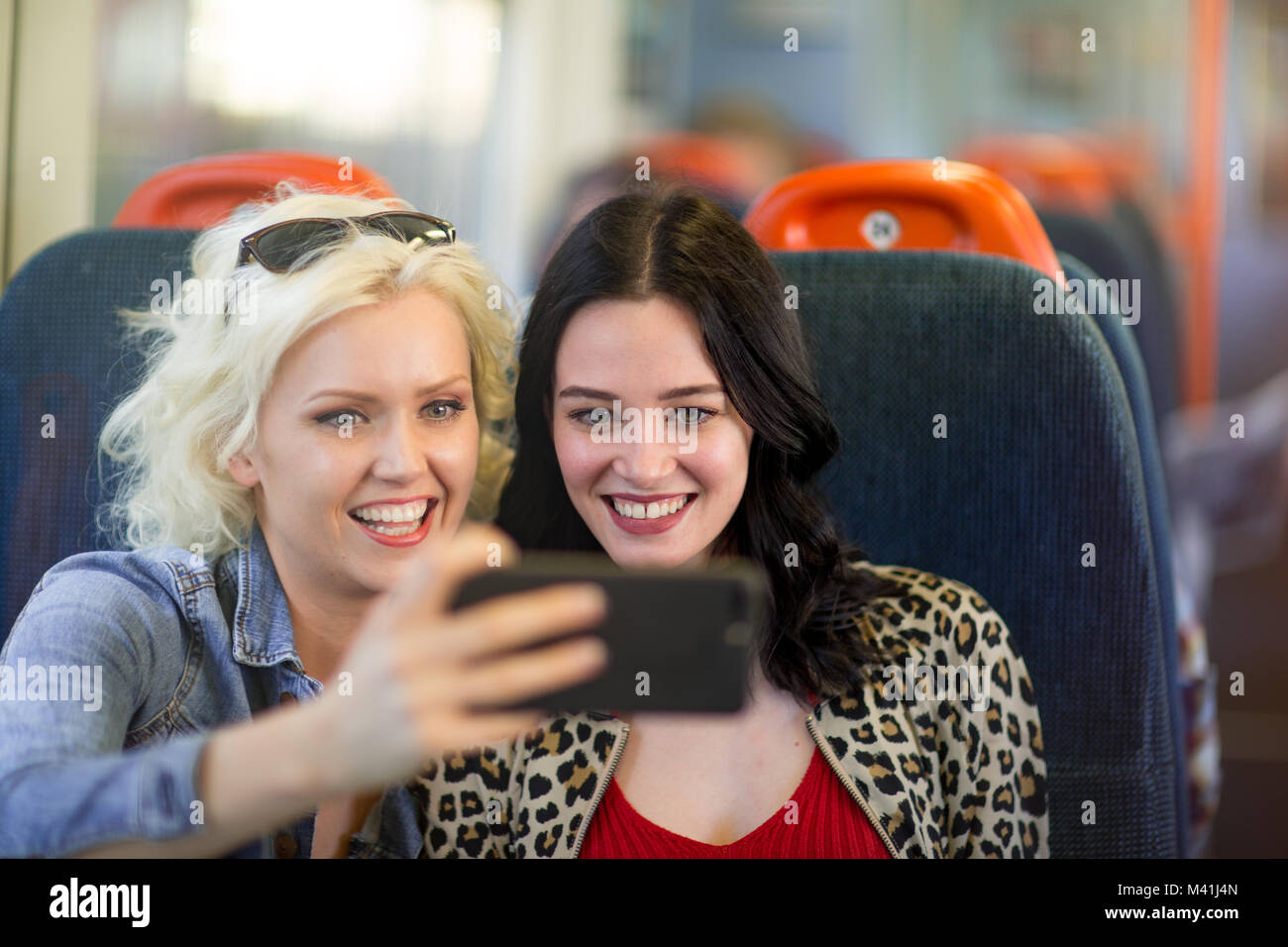 Les jeunes femelles adultes amis voyageant sur le train prenant selfies Banque D'Images