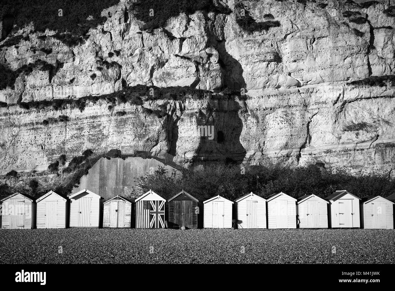 Rangée de cabines de plage dans la région de Beer, Devon en noir et blanc. Banque D'Images