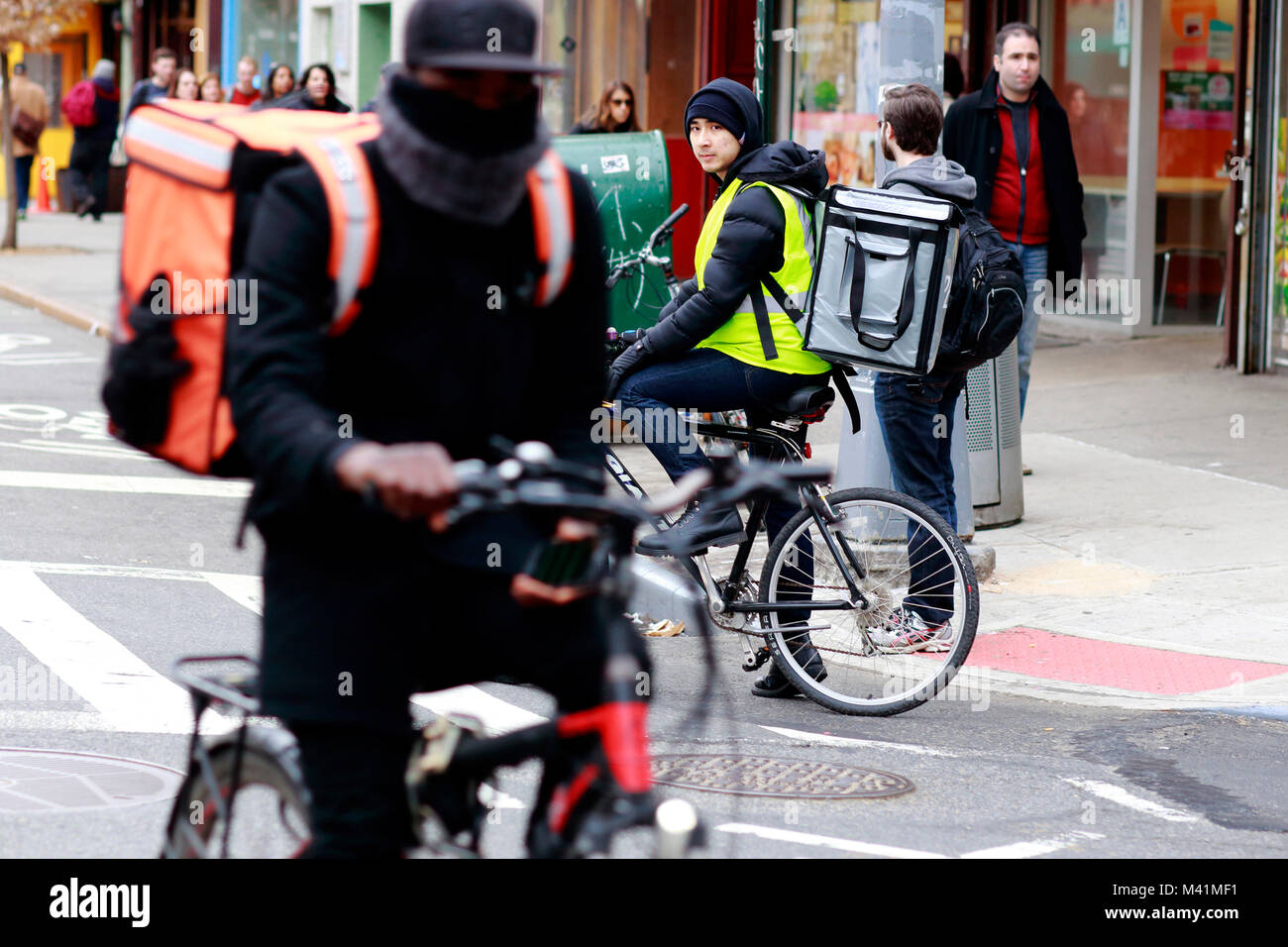 Livraison de nourriture messagers de vélo portant des sacs de vélo isolés thermiques de la concurrence sur les services de livraison de nourriture à la demande à New York, NY. Banque D'Images