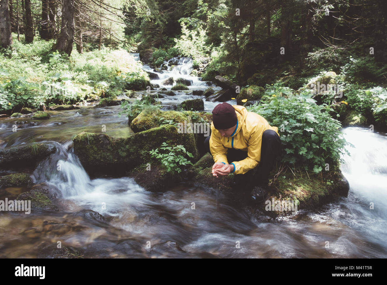 Homme boire l'eau de ruisseau de montagne clair Banque D'Images