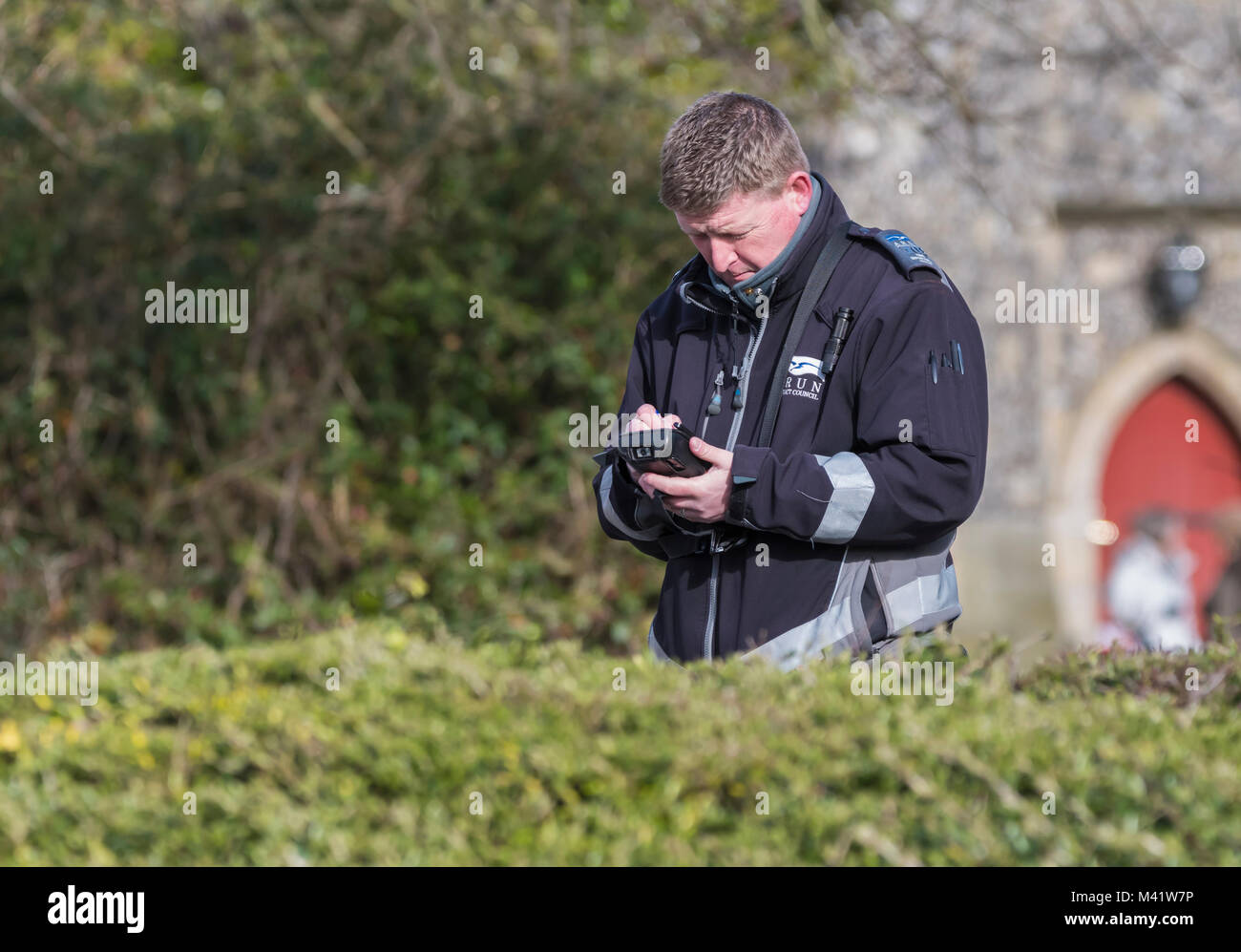 Directeur de trafic l'écriture d'un billet de stationnement pour une voiture en stationnement illégal en Angleterre, Royaume-Uni. Parking gratuit avis de sanction. Banque D'Images