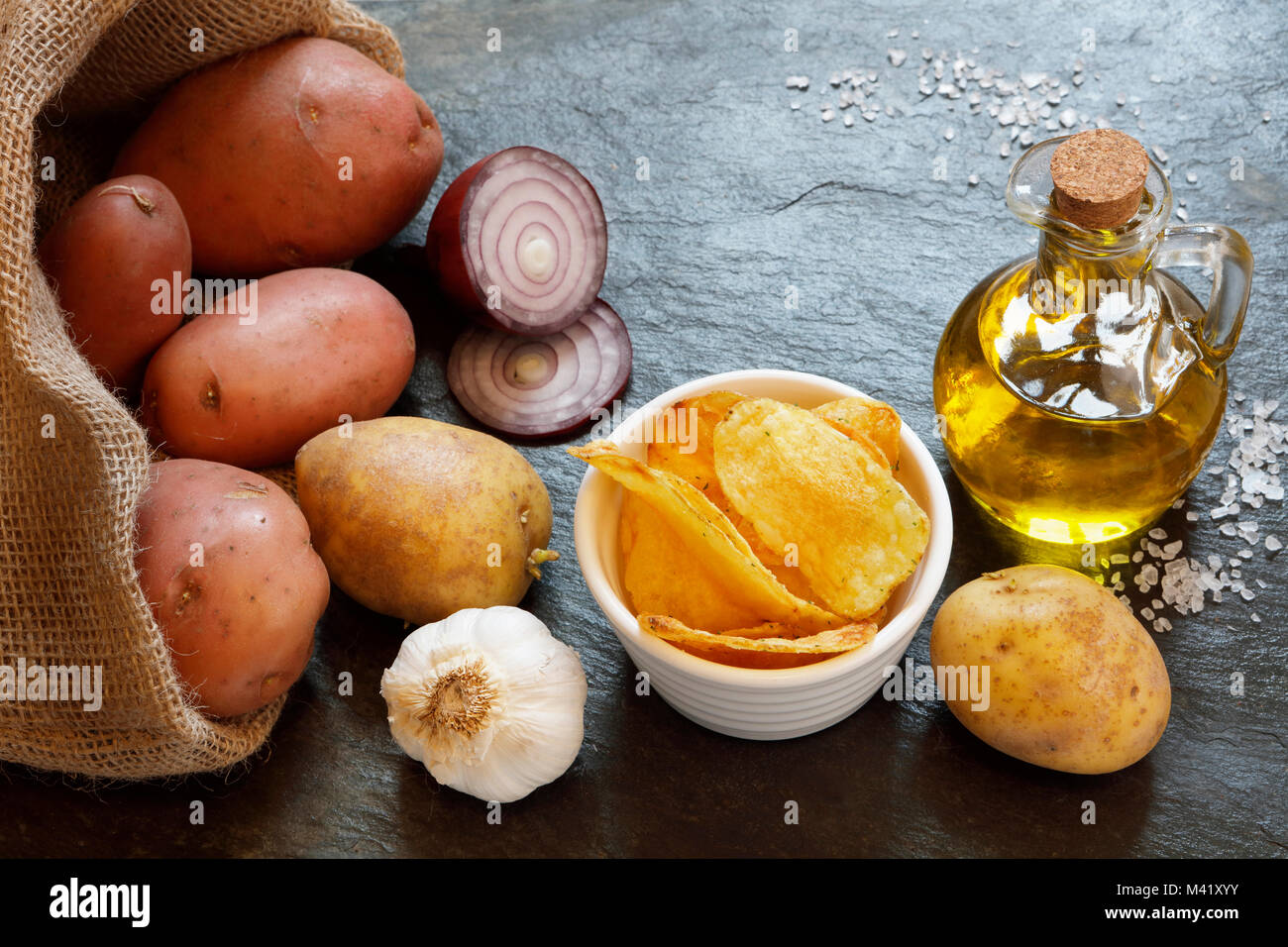 Les pommes de terre à chips oignon rouge, huile d'olive, l'ail et de sel de roche, sur table ardoise with copy space Banque D'Images