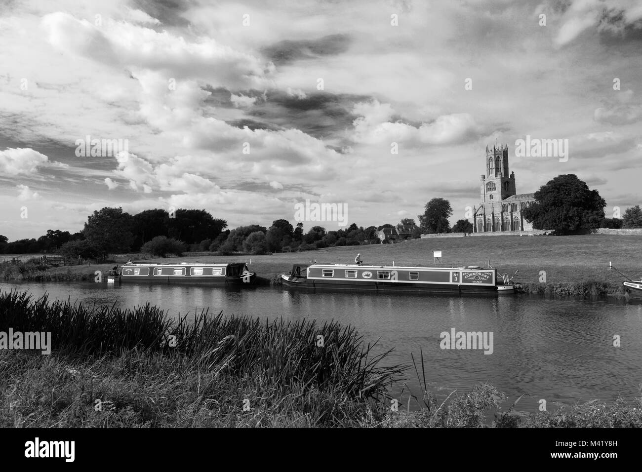 Narrowboats sur la rivière Nene ; St Mary and All Saints Church ; village ; Fotheringhay Northamptonshire, Angleterre, Royaume-Uni Banque D'Images