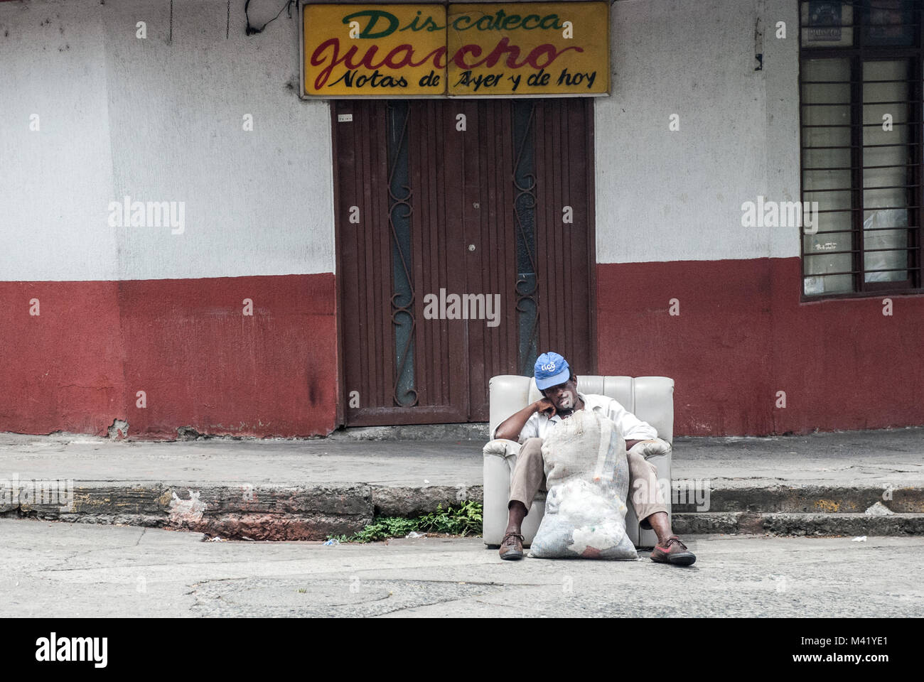 Sans-abri d'un homme noir se reposant dans un fauteuil en face d'une boîte de nuit dans une rue de Cali, Colombie Banque D'Images