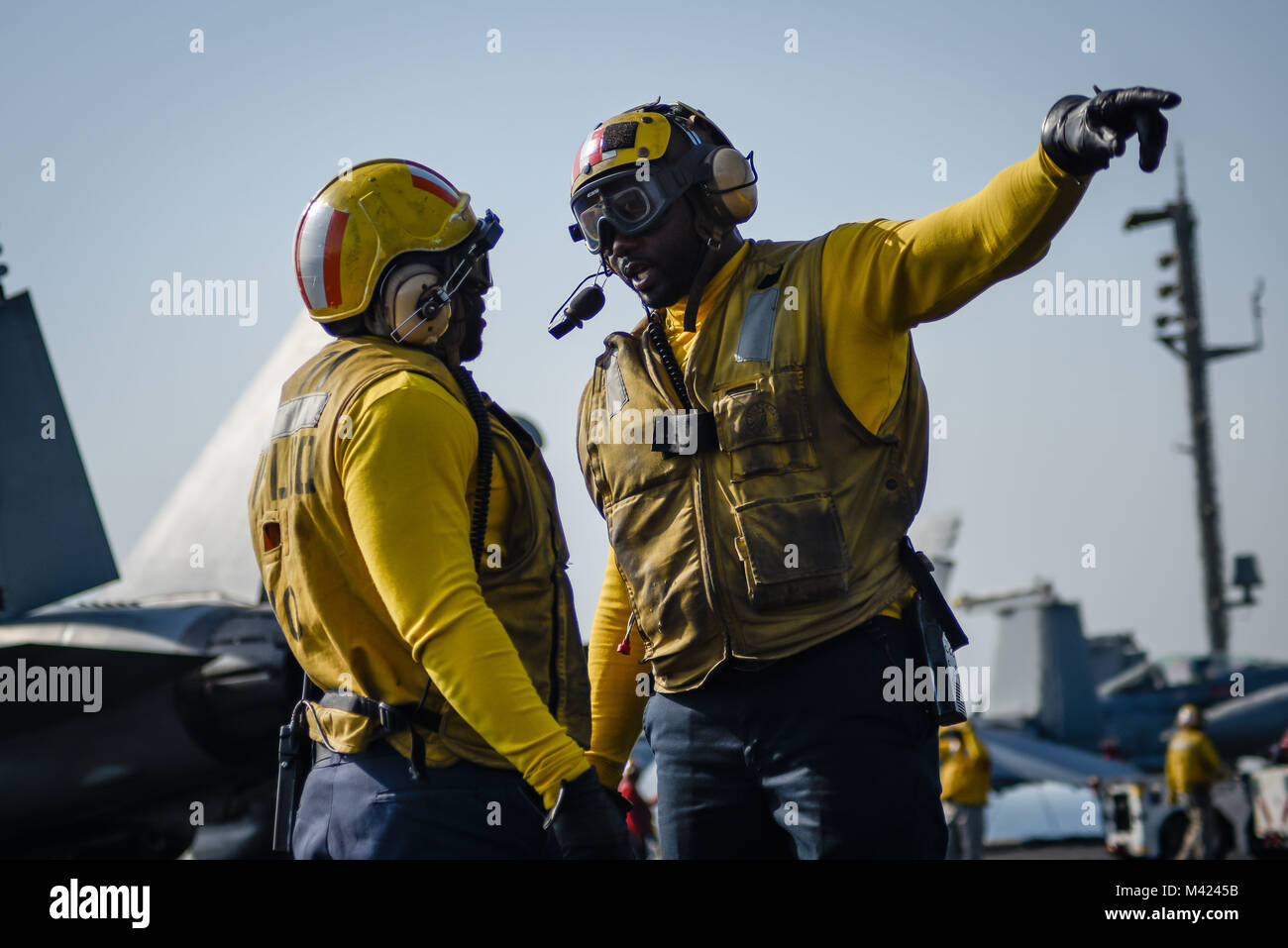 180115-N-VN584-1728 Golfe Arabique (jan. 15, 2018) l'Aviation maître de Manœuvre (manutention) 1re classe Edmond Scott, à gauche, et l'Aviation maître de Manœuvre (manutention) 1re classe Paul Hall discuter des opérations de vol sur le pont du porte-avions USS Theodore Roosevelt (CVN 71). Theodore Roosevelt et son groupe aéronaval sont déployés dans le domaine de la 5e flotte américaine des opérations à l'appui des opérations de sécurité maritime pour rassurer les alliés et les partenaires et de préserver la liberté de navigation et la libre circulation du commerce dans la région. (U.S. Photo par marine Spécialiste de la communication de masse de la classe de 3ème Banque D'Images