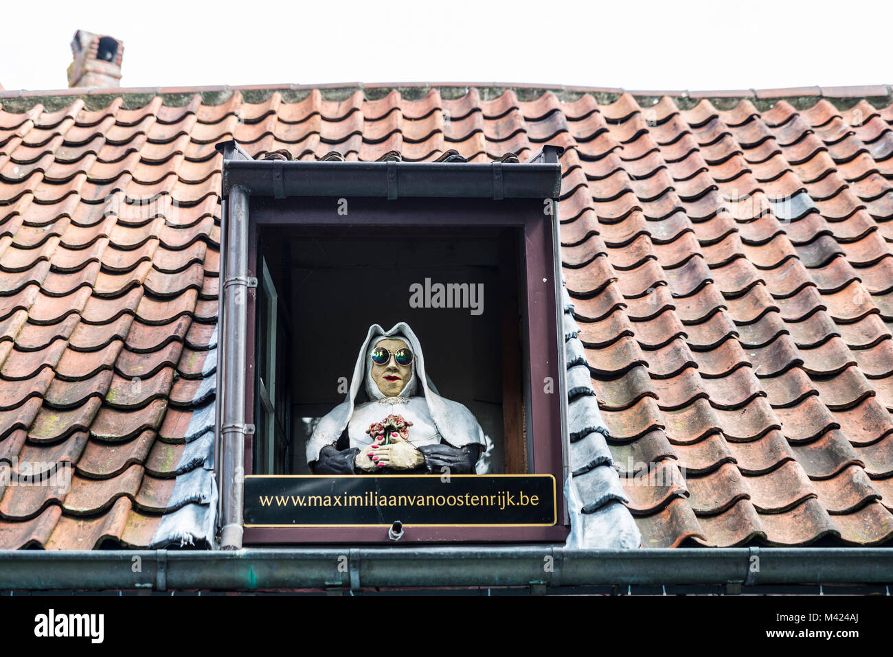 Bruges, Belgique - 1 septembre 2017 : statue religieuse avec des lunettes de soleil sur la fenêtre d'un toit que la publicité pour un restaurant bar dans le vieux centre historique Banque D'Images