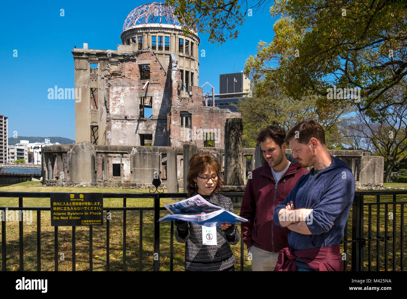 Guide touristique et les touristes à le dôme de la bombe atomique dans le parc de la paix, Hiroshima, Japon Banque D'Images