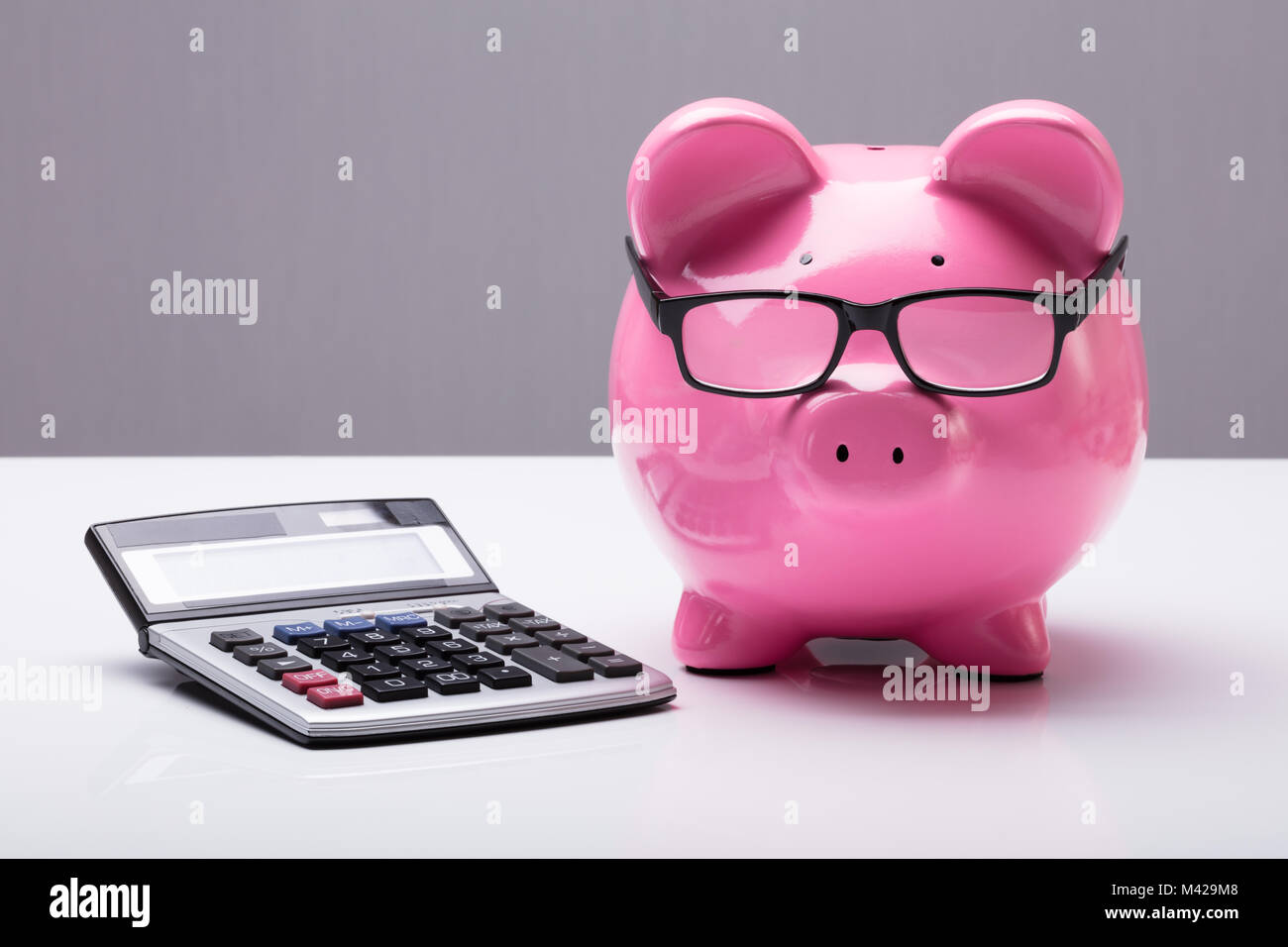 Close-up d'une tirelire avec les lunettes et Calculatrice sur 24 Banque D'Images