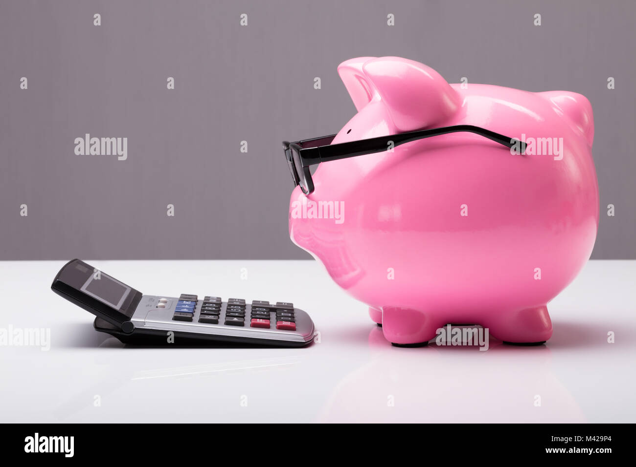 Close-up d'une tirelire avec les lunettes et Calculatrice sur 24 Banque D'Images