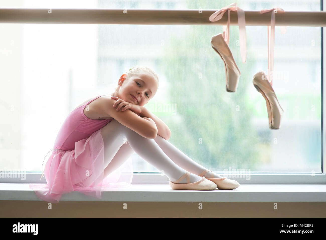 Ballet Happy teen girl sitting on windowsill. Jolie ballerine ballet de  chambre. Paire de chaussures de ballet de pointe sur barre Photo Stock -  Alamy