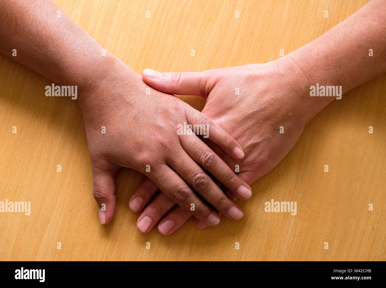 Regardant vers le bas sur deux cinquante ans, Mains et avant-bras placés  dessus de l'autre, la meilleure main est asiatique et le bas côté est de  race blanche, le Photo Stock -